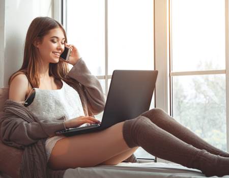 Call-girl-playing-computer-sitting-on-the-windowsill-Stock-Photo